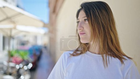 Foto de Mujer rubia joven mirando a un lado con expresión seria en la calle - Imagen libre de derechos