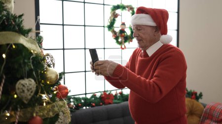 Téléchargez les photos : Senior prendre des photos de l'arbre de Noël à la maison - en image libre de droit