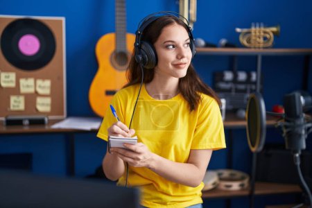 Foto de Young woman musician composing song at music studio - Imagen libre de derechos