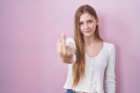Photo for Young caucasian woman standing over pink background showing middle finger, impolite and rude fuck off expression - Royalty Free Image