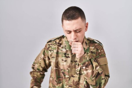 Foto de Joven con uniforme camuflaje del ejército sintiéndose mal y tosiendo como síntoma de frío o bronquitis. concepto de atención sanitaria. - Imagen libre de derechos