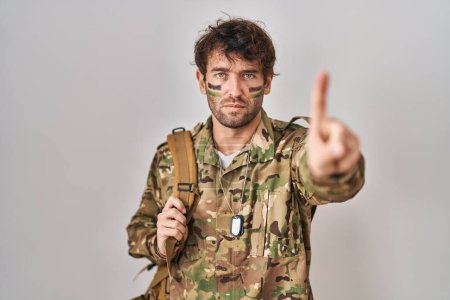 Photo for Hispanic young man wearing camouflage army uniform pointing with finger up and angry expression, showing no gesture - Royalty Free Image