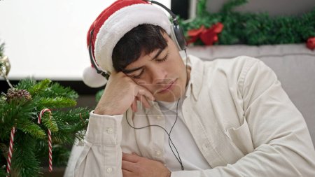 Foto de Joven hispano durmiendo en el sofá junto al árbol de Navidad en casa - Imagen libre de derechos