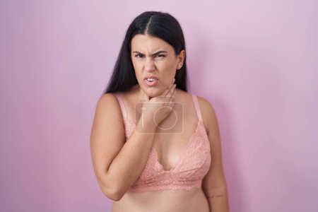 Photo for Young hispanic woman wearing pink bra touching painful neck, sore throat for flu, clod and infection - Royalty Free Image