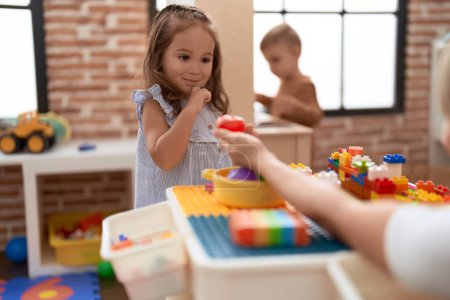 Foto de Adorable chica y niño jugando con comida juguete de plástico sentado en la mesa en el jardín de infantes - Imagen libre de derechos