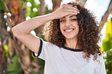 Photo for Hispanic woman with curly hair standing outdoors stressed and frustrated with hand on head, surprised and angry face - Royalty Free Image