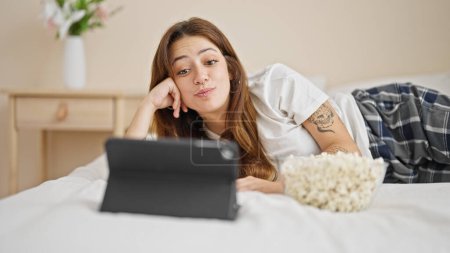 Photo for Young beautiful hispanic woman watching movie lying on bed at bedroom - Royalty Free Image