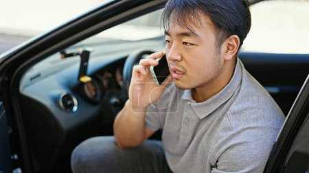 Téléchargez les photos : Parler sur smartphone assis sur la voiture à la rue - en image libre de droit