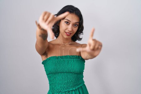 Téléchargez les photos : Jeune femme hispanique debout sur fond isolé faisant cadre en utilisant les mains paumes et les doigts, perspective de la caméra - en image libre de droit