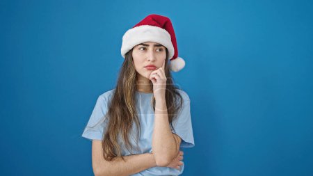 Photo for Young beautiful hispanic woman wearing christmas hat with doubt expression over isolated blue background - Royalty Free Image