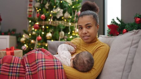 Photo for Mother and son celebrating christmas breastfeeding baby at home - Royalty Free Image
