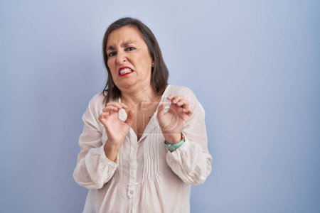 Photo for Middle age hispanic woman standing over blue background disgusted expression, displeased and fearful doing disgust face because aversion reaction. - Royalty Free Image