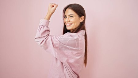 Téléchargez les photos : Jeune belle femme hispanique souriant confiant faire un geste fort avec le bras sur fond rose isolé - en image libre de droit