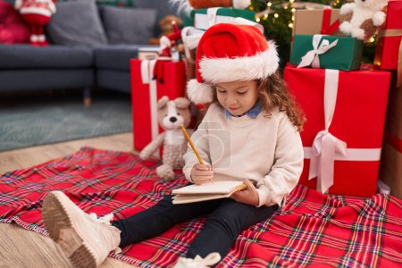 Photo for Adorable blonde toddler writing santa claus letter sitting on floor by christmas gifts at home - Royalty Free Image