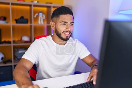 Téléchargez les photos : Jeune homme latin streamer jouer à un jeu vidéo en utilisant l'ordinateur à la salle de jeux - en image libre de droit