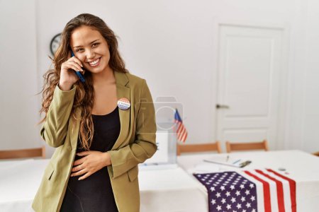 Photo for Young beautiful hispanic woman electoral table president talking on smartphone at electoral college - Royalty Free Image