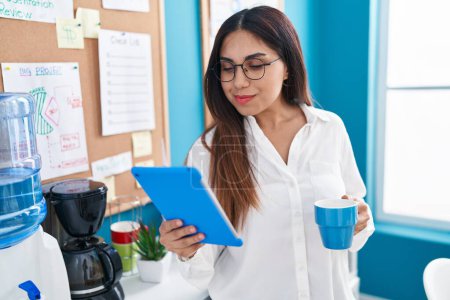 Foto de Joven hermosa mujer árabe trabajador de negocios utilizando touchpad beber café en la oficina - Imagen libre de derechos