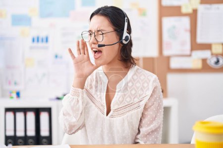 Photo for Hispanic young woman working at the office wearing headset and glasses clueless and confused with open arms, no idea and doubtful face. - Royalty Free Image