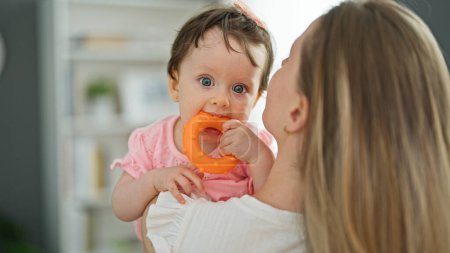 Photo for Mother and daughter hugging each other sucking toy at home - Royalty Free Image