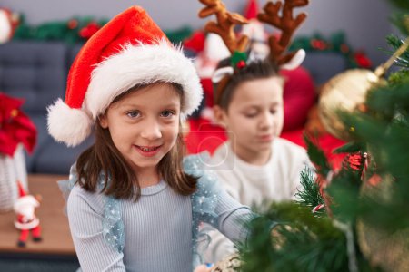 Foto de Adorable niño y niña decorando el árbol de Navidad en casa - Imagen libre de derechos