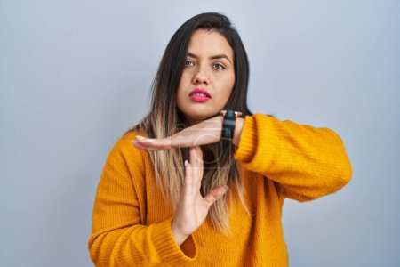 Photo for Young hispanic woman standing over isolated background doing time out gesture with hands, frustrated and serious face - Royalty Free Image