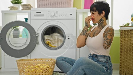 Foto de Mujer hispana con brazo amputado lavando ropa oliendo ropa sucia en la lavandería - Imagen libre de derechos