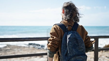 Foto de Joven turista hispano con mochila al revés en la playa - Imagen libre de derechos