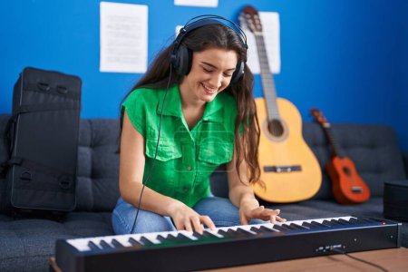Foto de Joven músico hispano tocando el teclado de piano en el estudio de música - Imagen libre de derechos