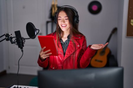 Téléchargez les photos : Jeune femme brune chantant une chanson à l'aide d'un microphone célébrant l'accomplissement avec un sourire heureux et une expression gagnante avec une main levée - en image libre de droit
