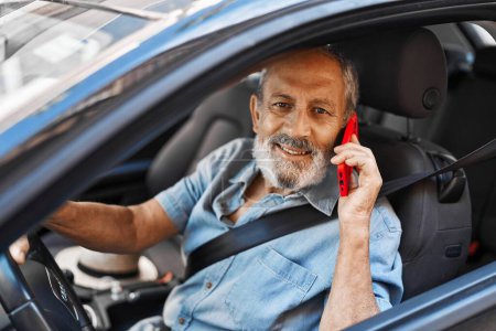 Téléchargez les photos : Senior homme aux cheveux gris parler sur smartphone assis sur la voiture à la rue - en image libre de droit