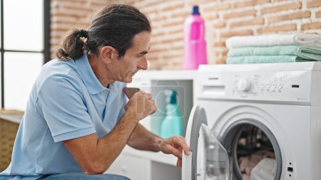 Photo for Middle age man washing clothes at laundry room - Royalty Free Image
