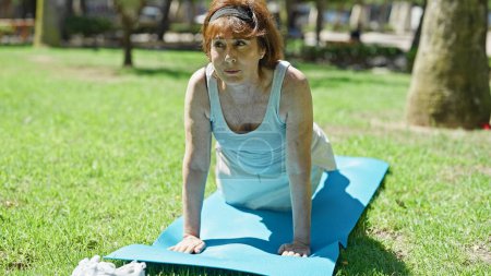 Photo for Middle age woman training push up on yoga mat at park - Royalty Free Image