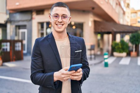 Photo for Young hispanic man executive smiling confident using smartphone at street - Royalty Free Image