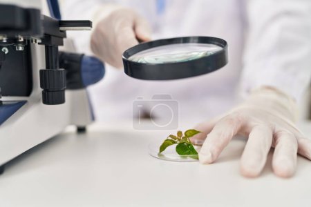 Foto de Joven caucásico hombre científico buscando planta muestra con loupe en laboratorio - Imagen libre de derechos