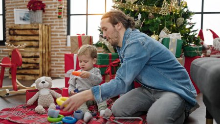 Foto de Padre e hijo celebrando la Navidad jugando con juguetes en casa - Imagen libre de derechos