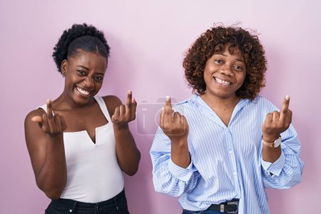 Photo for Two african women standing over pink background showing middle finger doing fuck you bad expression, provocation and rude attitude. screaming excited - Royalty Free Image
