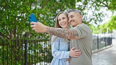 Foto de Hombre y mujer pareja sonriendo confiado hacer selfie por teléfono inteligente en el parque - Imagen libre de derechos