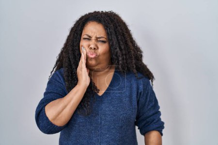 Photo for Plus size hispanic woman standing over white background touching mouth with hand with painful expression because of toothache or dental illness on teeth. dentist - Royalty Free Image