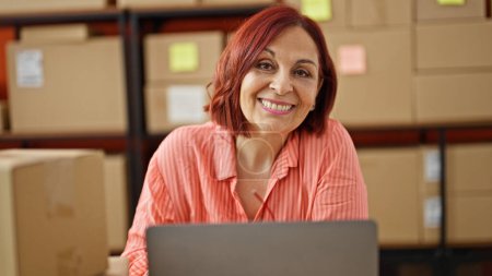Foto de Mujer de mediana edad comercio electrónico de negocios sonriendo en la oficina - Imagen libre de derechos