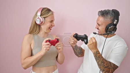 Photo for Man and woman couple playing video game smiling over isolated pink background - Royalty Free Image