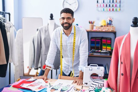 Téléchargez les photos : Jeune tailleur arabe souriant confiant debout au magasin de tailleur - en image libre de droit