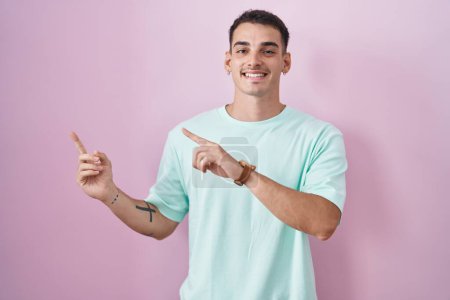 Photo for Handsome hispanic man standing over pink background smiling and looking at the camera pointing with two hands and fingers to the side. - Royalty Free Image