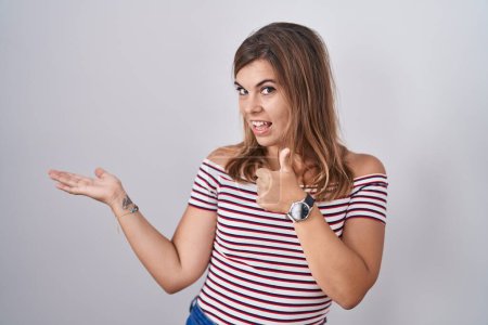 Photo for Young hispanic woman standing over isolated background showing palm hand and doing ok gesture with thumbs up, smiling happy and cheerful - Royalty Free Image