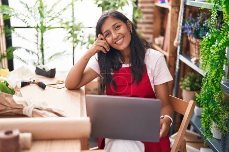 Photo for Young beautiful hispanic woman florist smiling confident using laptop at flower shop - Royalty Free Image