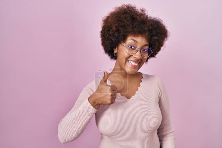 Téléchargez les photos : Jeune femme afro-américaine debout sur fond rose faisant des pouces heureux geste avec la main. approuvant l'expression regardant la caméra montrant le succès. - en image libre de droit