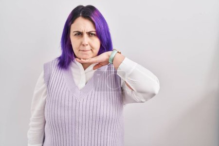 Téléchargez les photos : Plus taille femme avec des cheveux violets debout sur fond blanc couper la gorge avec la main comme couteau, menacer d'agression avec une violence furieuse - en image libre de droit