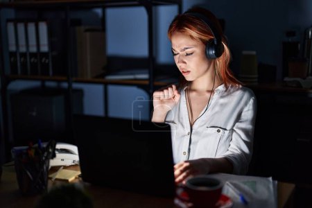 Téléchargez les photos : Jeune femme caucasienne travaillant au bureau la nuit se sentant mal et toussant comme symptôme de rhume ou de bronchite. concept de soins de santé. - en image libre de droit