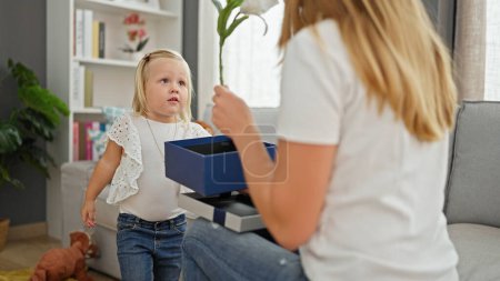 Photo for Mother and daughter's heartwarming birthday surprise at home, caucasian mum gifting her little girl a fascinating flower present, igniting party mood indoors - Royalty Free Image