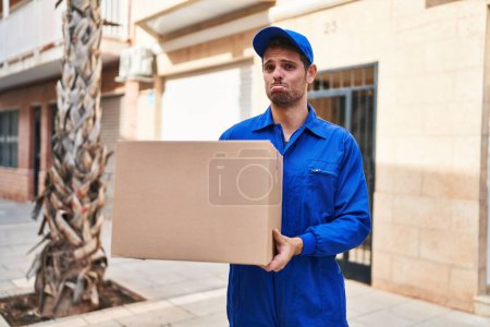 Photo for Young hispanic man delivering box depressed and worry for distress, crying angry and afraid. sad expression. - Royalty Free Image