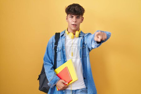 Photo for Hispanic teenager wearing student backpack and holding books pointing displeased and frustrated to the camera, angry and furious with you - Royalty Free Image